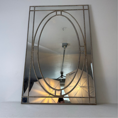 Decorative wall mirror with a metallic frame on a white surface.