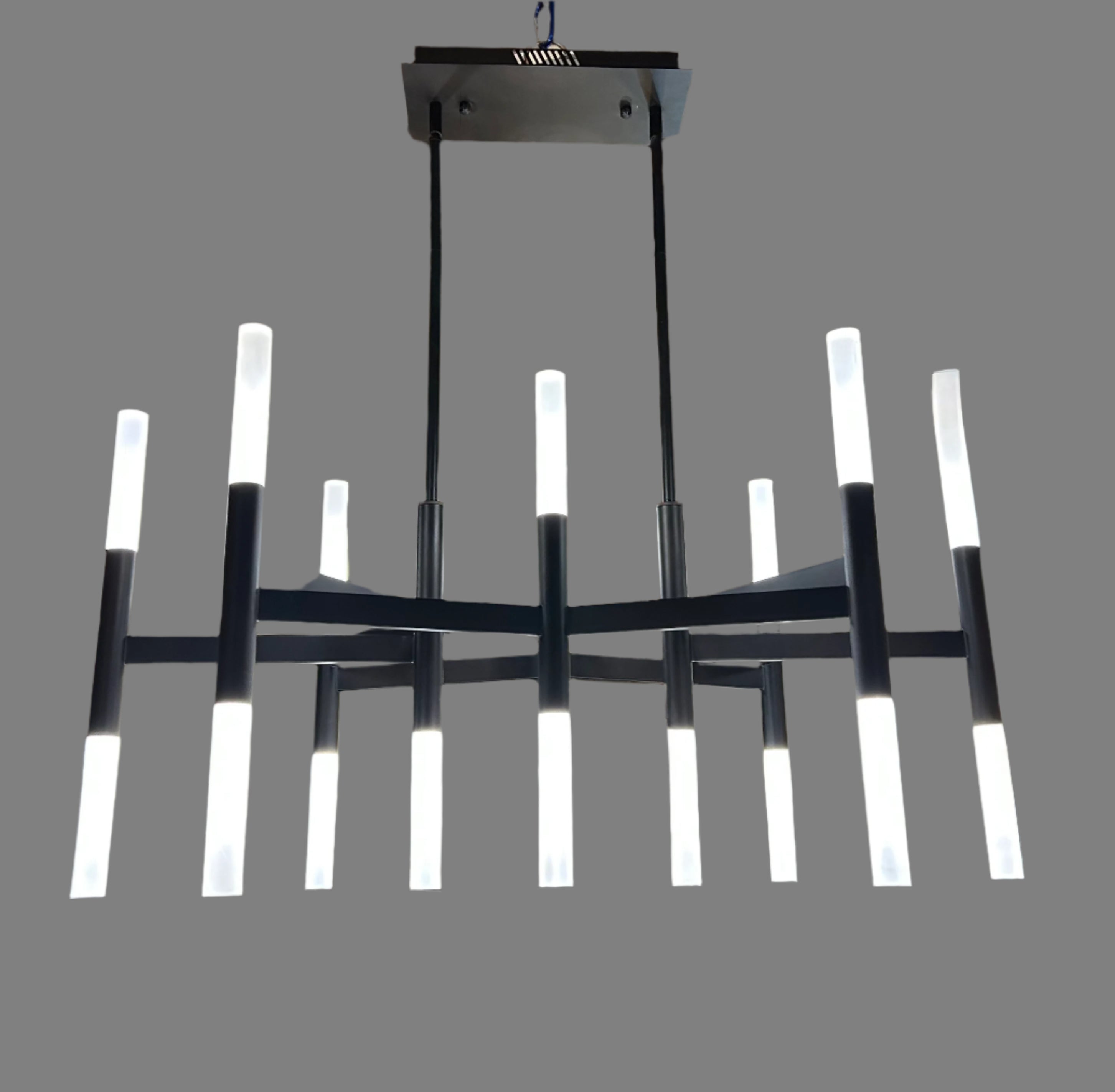 Modern chandelier hanging in a rustic interior setting with wooden beams and brick walls.