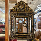 Decorative gold-framed mirror with intricate designs in a store setting