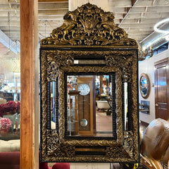 Decorative gold-framed mirror with intricate designs in a store setting