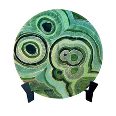 Decorative plate with green circular patterns on a stand indoors.
