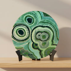 Decorative plate with green circular patterns on a stand indoors.