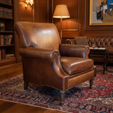 Brown leather armchair in a room with wooden floors and various items in the background