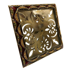 Decorative metal frame with intricate cut-out design on a white surface