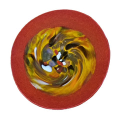 Colorful swirl design on a red plate against a wooden background