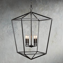 Decorative black chandelier with three lit lights against a textured gray wall.