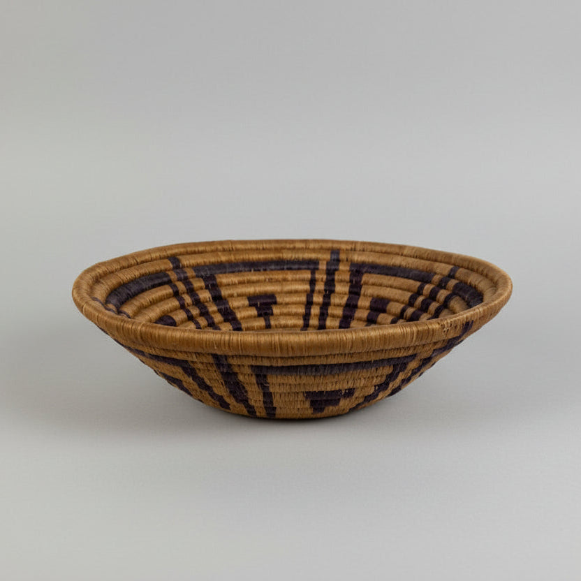 Woven basket with geometric pattern on a textured surface and brick wall background