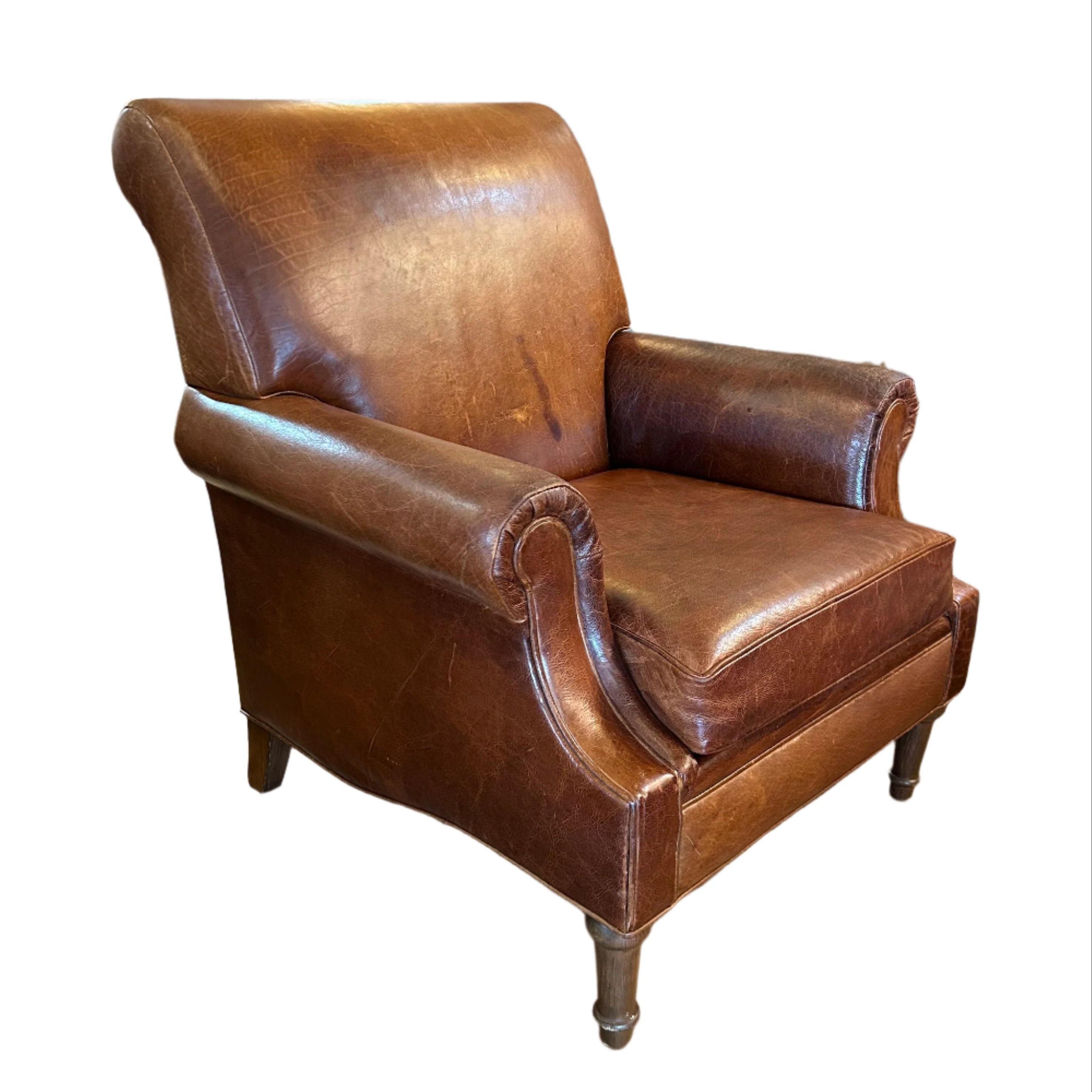 Brown leather armchair in a room with wooden floors and various items in the background