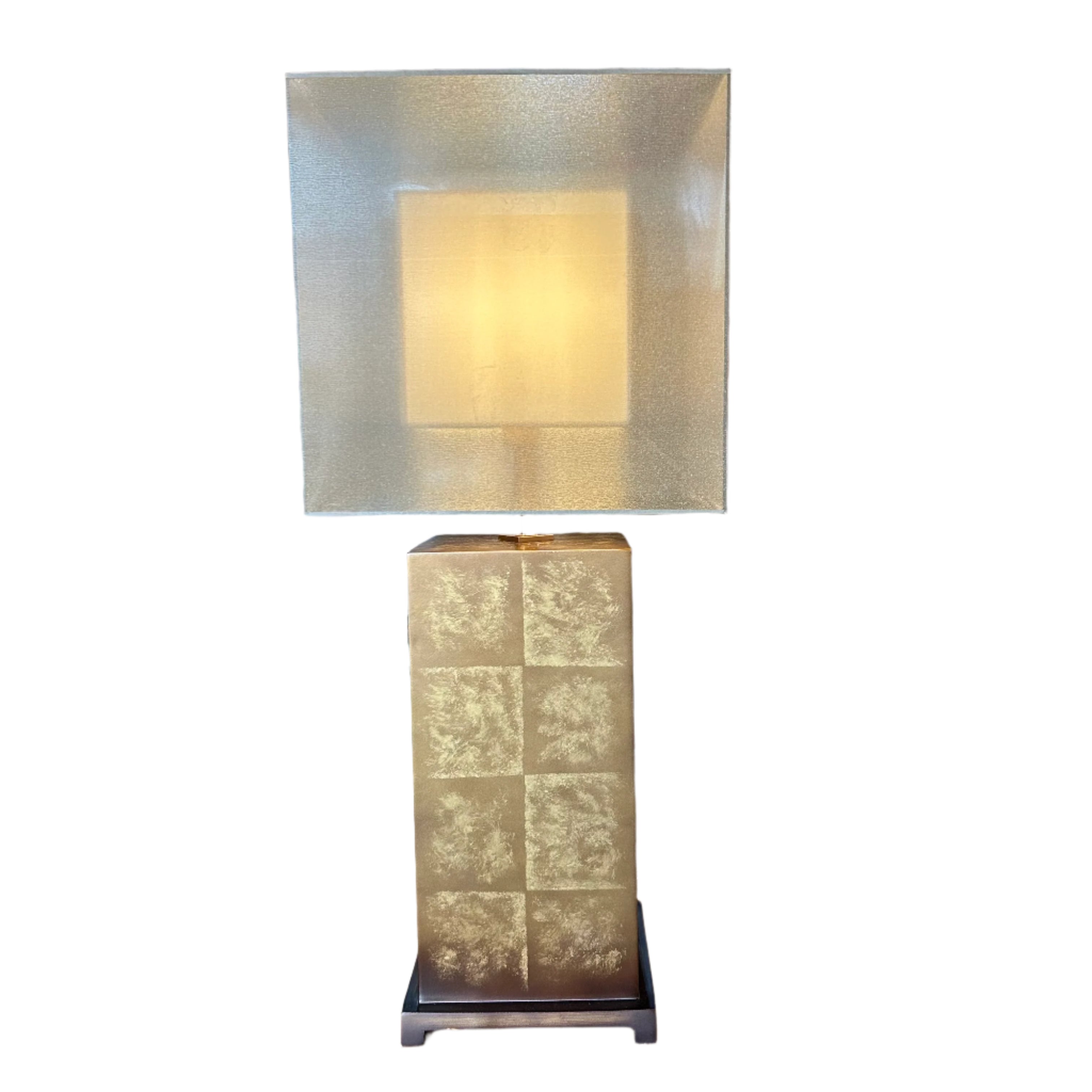 Tall decorative lamp with a textured square design on a wooden table in a showroom setting.