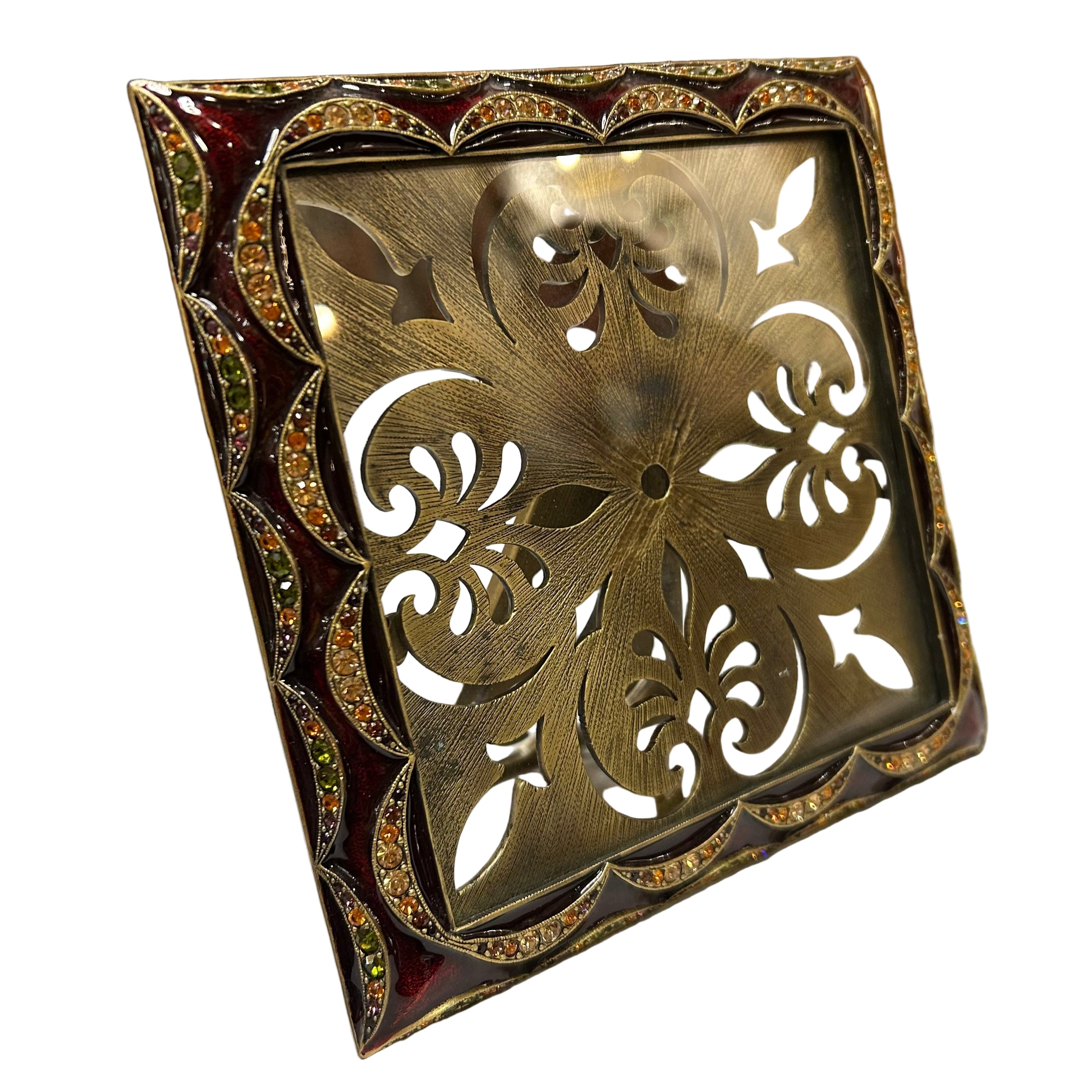 Decorative metal frame with intricate cut-out design on a white surface